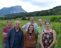 groupe de six personnes dans une parcelle de vigne avec des montagnes en arrière plan